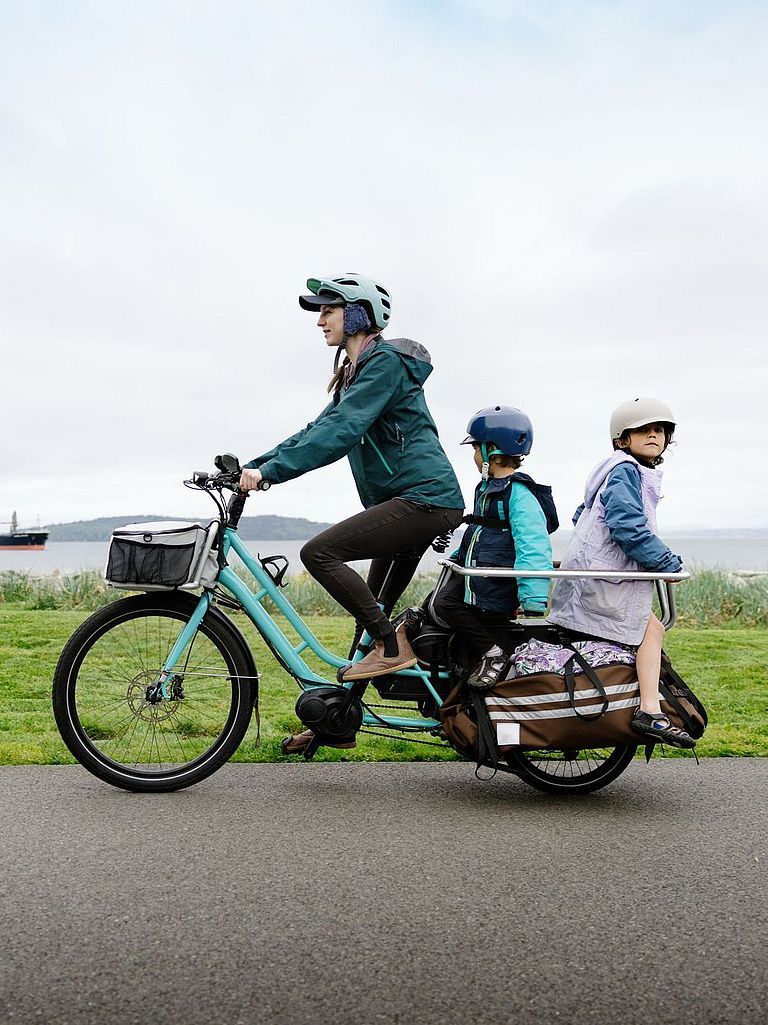 Mutter mit ihren Kindern in einem Lastenfahrrad