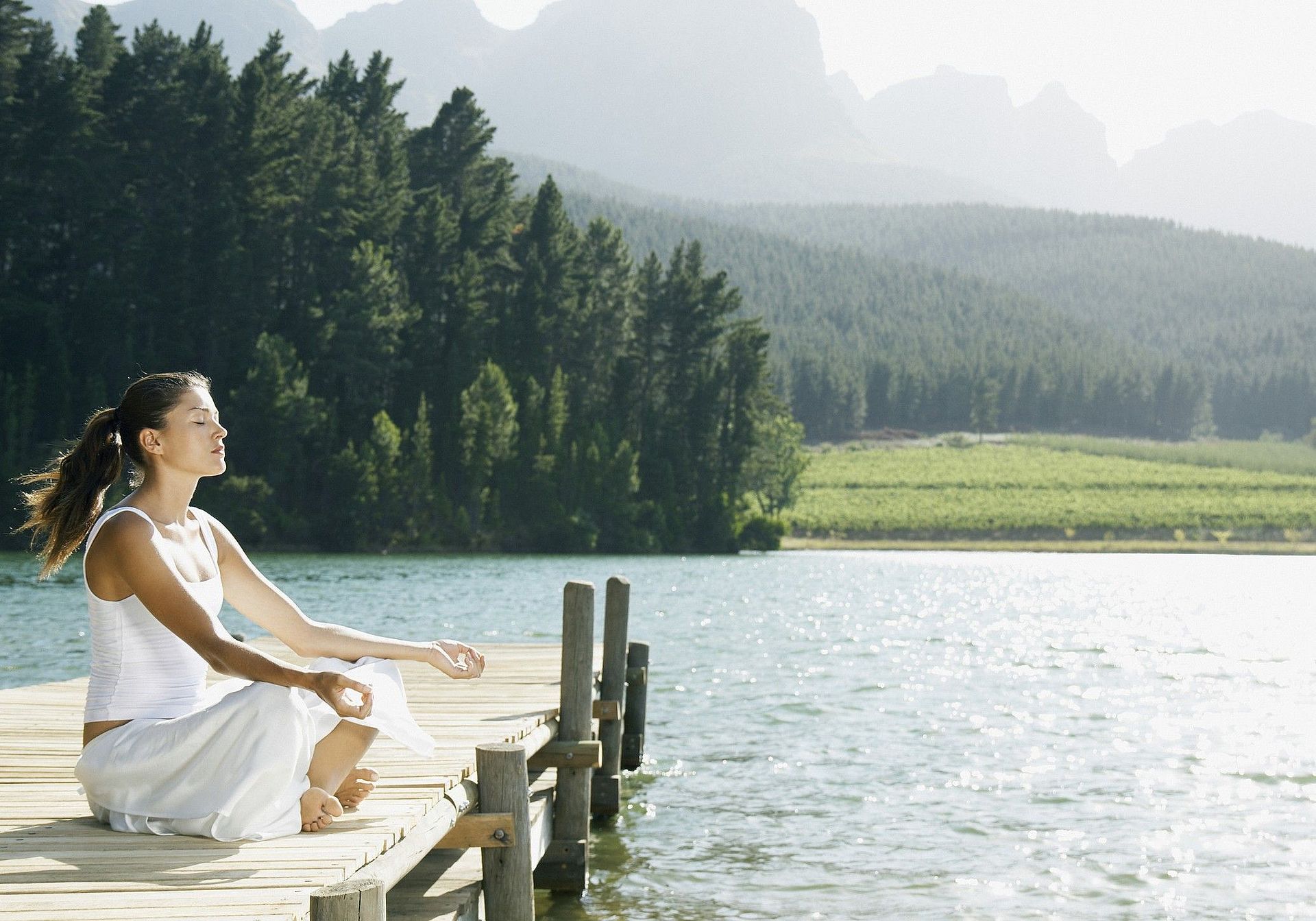 Eine Frau macht Yoga auf dem Steg an einem See