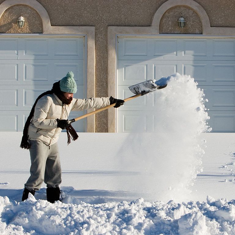Ein Mann räumt Schnee vor seinem Haus