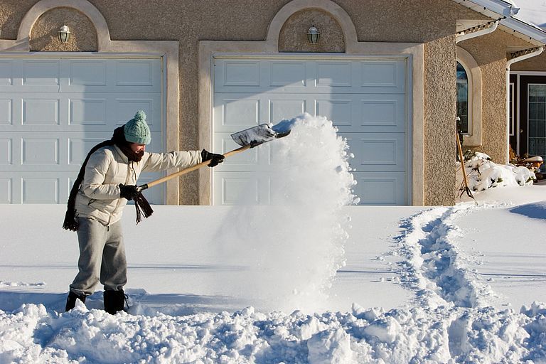 Ein Mann räumt Schnee vor seinem Haus
