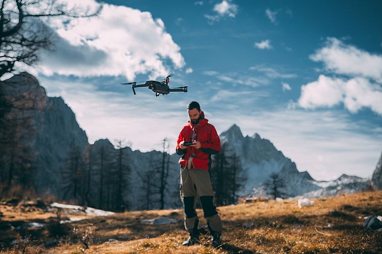 Mann mit Drohne in den Bergen