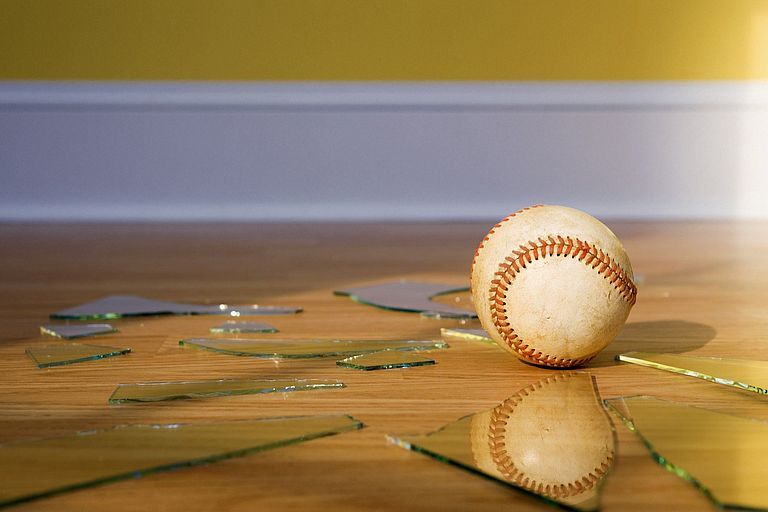 Baseball mitten in den Scherben einer Fensterscheibe