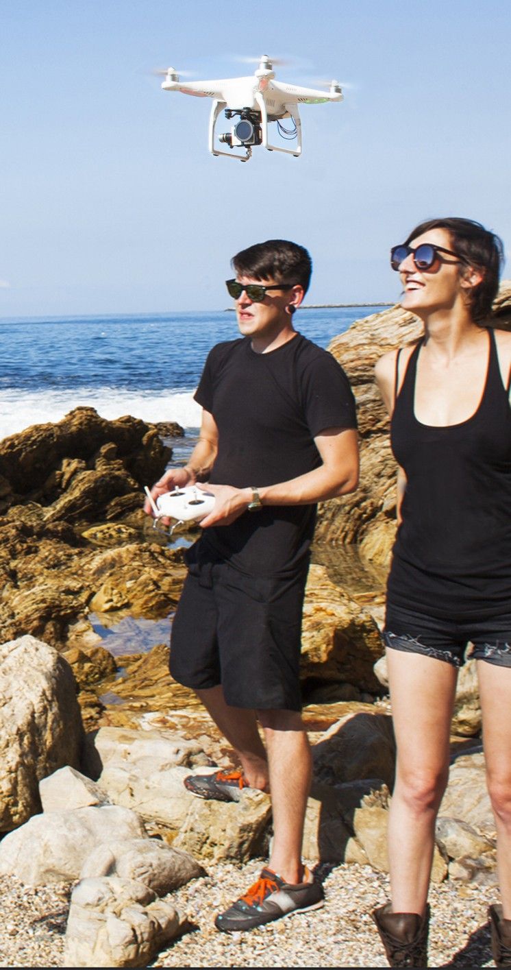 Junges Paar lässt am Meer eine Drohne fliegen