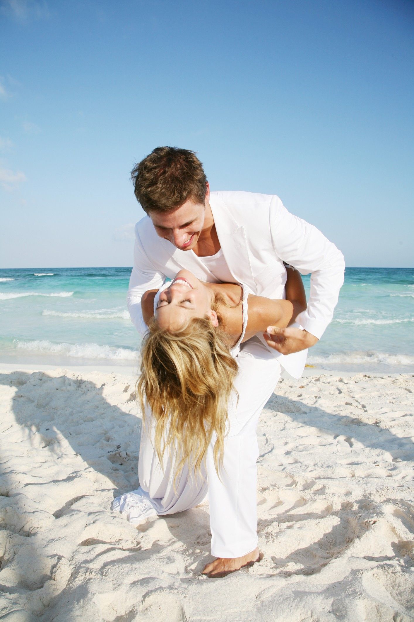 Verliebtes Hochzeitspaar in Weiß am Strand